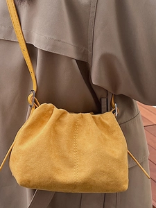 Minimalist yellow suede pleated crossbody bag with slim leather strap and gold ring detail