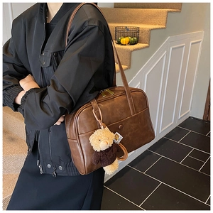 Detail der vintage braunen PU-Leder Boston Tasche mit Bärenanhänger an der Schulter