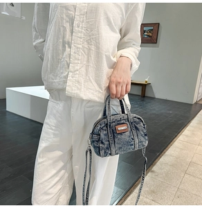 Close-up of vintage washed denim handbag with dual zippers and leather logo detail