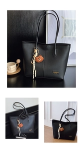 Detail of black litchi grain tote bag with fashion leather tag and bear charm accessory