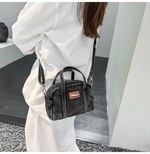 Side view of a vintage black washed denim crossbody bag with white contrast stitching