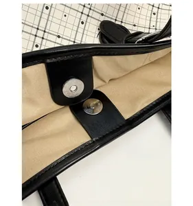 Detail of the magnetic buckle closure on a canvas and leather tote bag with inner lining