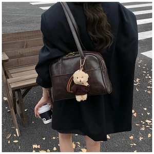 Dunkelbraune Boston-Tasche aus PU-Leder mit süßem Plüschbären-Anhänger auf der Straße