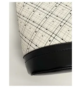 Detail view of the reinforced black leather base and stitching on the cream canvas tote bag
