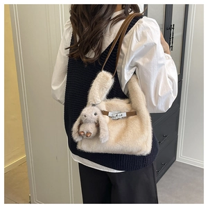 Détail d'un sac à main en peluche blanc cassé avec bandoulière en cuir et breloque lapin