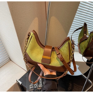 Close-up of vintage baguette bag featuring green suede material and gold metal buckle
