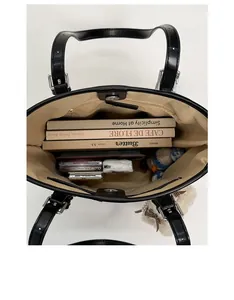 Spacious interior of black leather tote bag showing organized books and inner zipper pocket