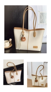 Detail view of large faux leather tote with brown teddy charm and striped scarf