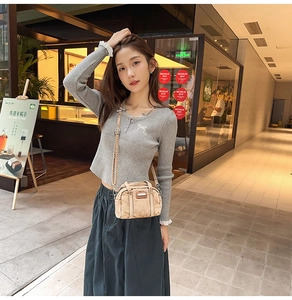 Distressed canvas crossbody bag with top handle worn by a model in casual street style