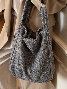 Grand sac fourre-tout gris en bouclée pour femme porté avec un trench-coat beige élégant