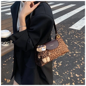 Close-up of leopard print crossbody bag with brown flap and cute bear plush charm detail