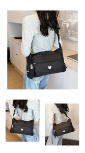 Détail du sac à bandoulière en nylon noir avec broderie ours et sangle réglable à cordon