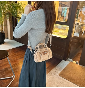 Close-up of vintage distressed denim handbag with wide jacquard strap in a cozy cafe