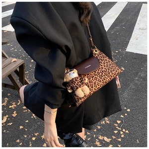 Close-up of leopard print crossbody bag with brown leather flap and cute bear pendant