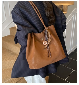 Brown large-capacity tote bag with matte texture and decorative donut pendant charms