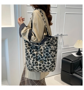 Close-up of leopard print plush tote bag with a metal logo on a model in a trench coat