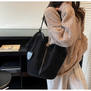 Detail showing the suede texture and leather trim of the large black tote shoulder bag