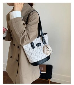 Detail of a contrast tote bag with white checkered fabric and black leather trim