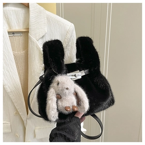 Gros plan d'un sac à main en peluche noire avec fermoir argenté et breloque lapin