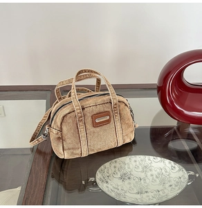 Detailed texture of brown distressed denim handbag with metallic accents and leather patch