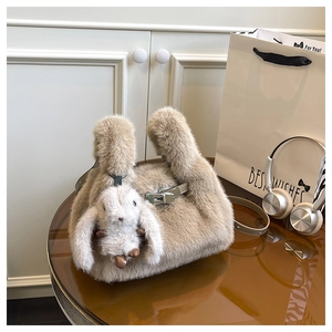 Détail d'un sac à main en peluche beige avec pendentif lapin et boucle en métal argenté
