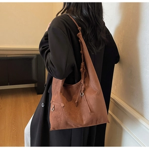 Detail einer dunkelbraunen Wildleder-Hobo-Tasche mit elegantem Fall und geknotetem Riemen