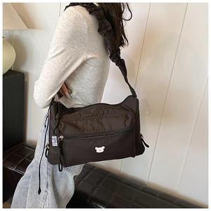 Détail du sac à bandoulière en nylon avec sangle à volants et logo ours blanc devant