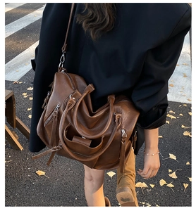 Brown vintage PU leather tote bag with tassel zippers shown in a street style back view