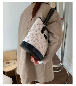 Classic cream quilted bucket bag with black leather trim shown on model's shoulder