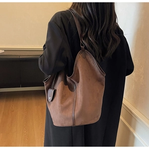 Detailed close-up of brown suede tote bag with vintage minimalist leather straps