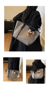 Détail du sac cabas gris en cuir avec anses noires et breloque en peluche sur modèle