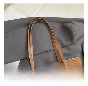 Detail view of brown suede tote bag with quilted diamond pattern on grey suit