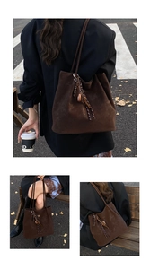 Detail of a large vintage brown suede tote bag with fringe charm and logo embroidery