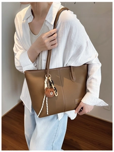 Close-up of dark brown lychee grain leather tote bag with cute bear charm detail