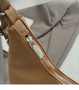 Dettaglio della cerniera in metallo argentato e trama martellata marrone su una borsa tote