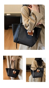 Détail du grand sac cabas noir avec de longues anses et un charme monstre en peluche