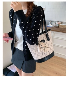 Chic quilted beige tote bag with black leather straps and a plush rabbit charm accessory