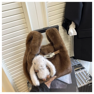 Détail d'un sac à main en peluche marron avec lanière en cuir et charm lapin blanc
