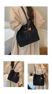 Macro detail of black suede tote bag featuring thin straps and beaded decorative knot