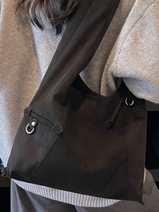 Minimalistische schwarze Canvas-Einkaufstasche mit breitem Gurt und silbernen Metallringen