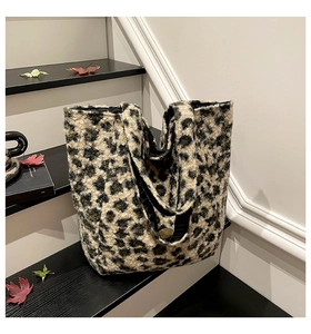 Detail of leopard print plush tote bag with gold logo on a stylish autumn leaf background