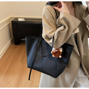 Détail du grand sac cabas noir en nylon avec pendentif en peluche et bandoulière plate