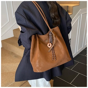 Detail view of large dark brown tote bag with metal logo and doughnut shaped charm