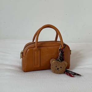 Detail der braunen Bowlingtasche mit Litschi-Textur, Metallreißverschluss und Teddybär