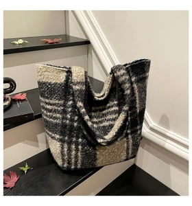Close-up of black and grey checkered faux shearling tote bag with a golden metal logo plate