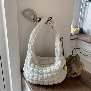 Detail of white quilted puffy cloud bag with soft bubble texture and yellow brand label