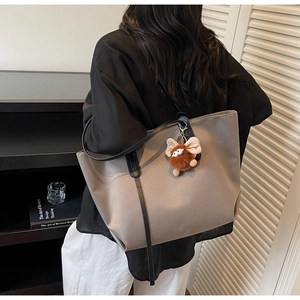 Détail du sac cabas kaki avec anses noires et un porte-clé en peluche mignon