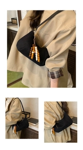 Dettaglio della borsa hobo con nappa in perline di legno colorate e texture scamosciata
