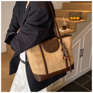 Detailed view of brown quilted tote bag with leather straps and decorative doughnut charm