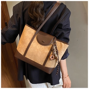 Detail of vintage beige quilted tote bag with brown leather trim and decorative charm